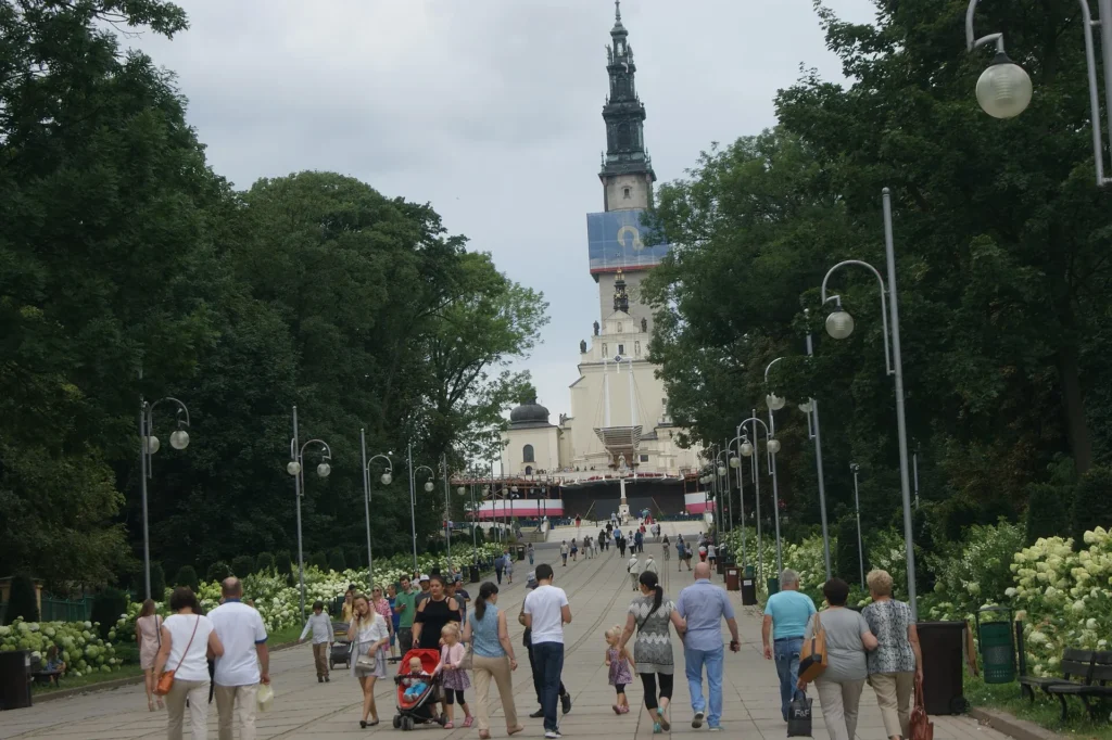 Visitors approaching Jasna Gora Monastery along a tree-lined avenue